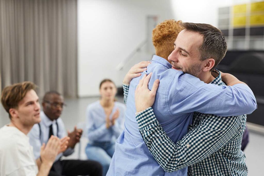 get involved during recovery, members of therapy group hugging being applauded