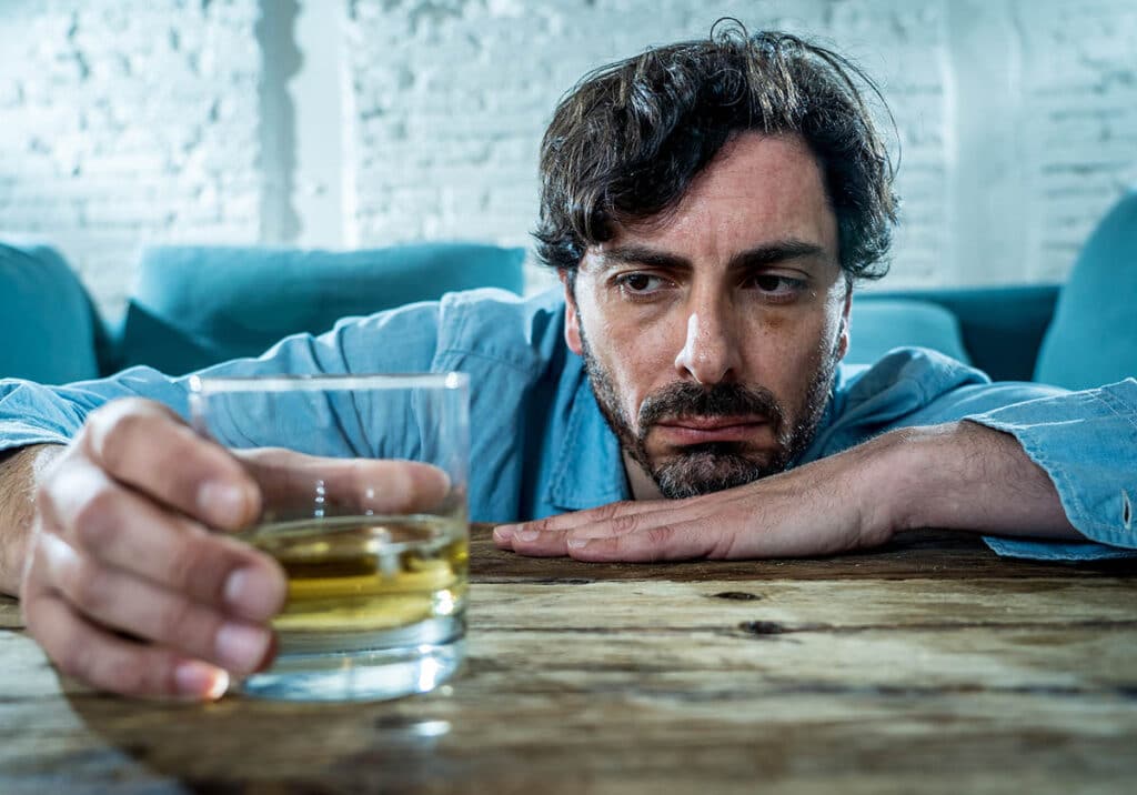 man staring at glass of liquor wondering how to quit drinking